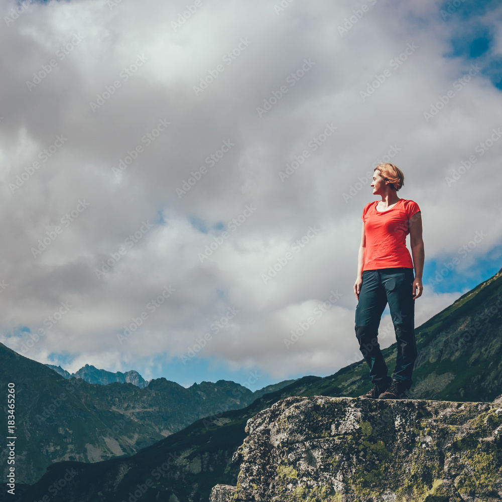 woman stands on the cliff and looks at the tops of mountains woman stands on the cliff and looks at the tops of mountains
