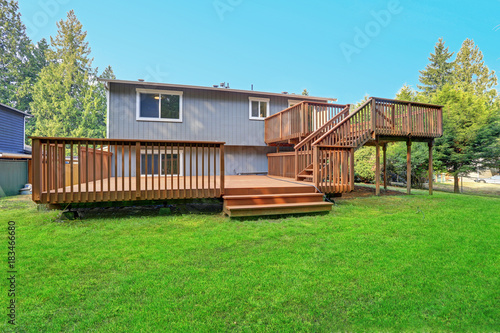 Fotografi Backyard view of grey rambler house with upper and lower decks