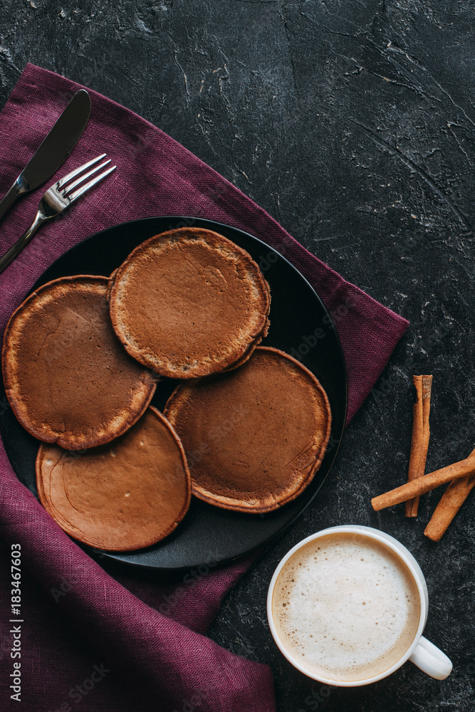 top view of chocolate pancakes and cup of coffee on black concrete surface top view of chocolate pancakes and cup of coffee on black concrete surface