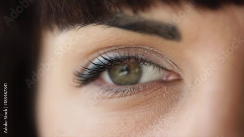 Woman is opening her green eyes, close-up shooting of one eye. Face of young brunette with make-up, looking inspirationally photo