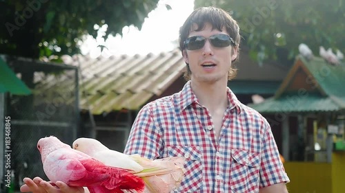 Happy man wearing sunglasses holds beautiful colorful pigeons. Doves sitting on hand owner and waving her beautiful wings in slow motion. 1920x1080