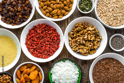 Ingredients of breakfast with healthy superfood on table, seeds, dry fruits, cereals, nuts, almonds, walnuts, goji berries, healthy food, flat lay, overhead