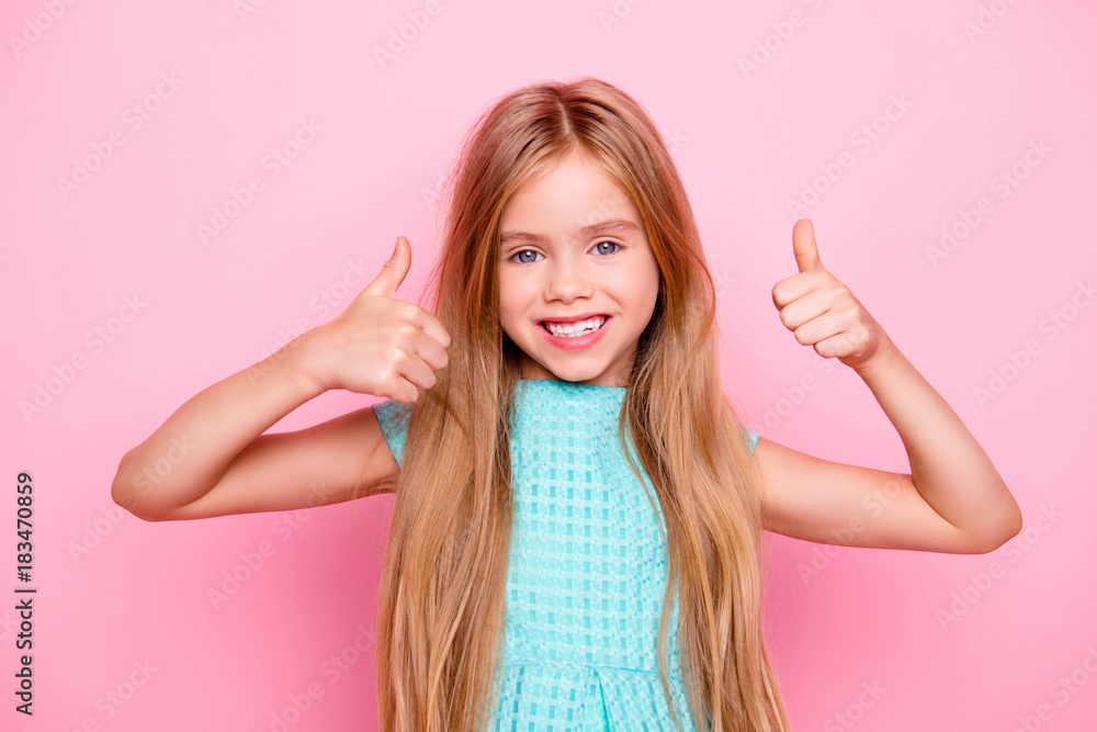Close up portrait of beautiful lovely cute joyful dreamy delightful little girl with toothy shiny beaming smile, wearing light blue dress is showing thumbs-up, isolated on bright pink background Close up portrait of beautiful lovely cute joyful dreamy delightful little girl with toothy shiny beaming smile, wearing light blue dress is showing thumbs-up, isolated on bright pink background