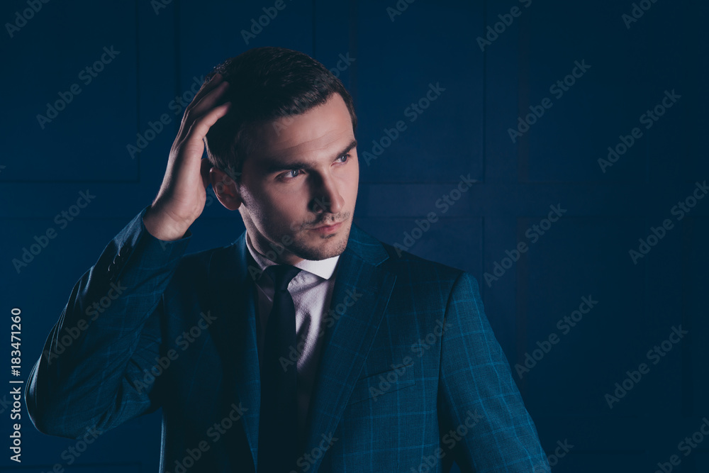 Close up portrait of cool, stunning, ideal, intelligent expert in formalwear with tie holding hand on hair, looking to the side over dark blue background Close up portrait of cool, stunning, ideal, intelligent expert in formalwear with tie holding hand on hair, looking to the side over dark blue background