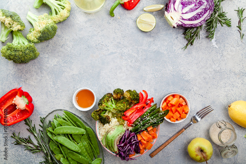 Tasty healthy bowl for lunch with couscous, baked broccoli and carrots cut in cubes, fried peas, avocados and red cabbage. Easy vegetarian diet concept. Rustic background, copy space.