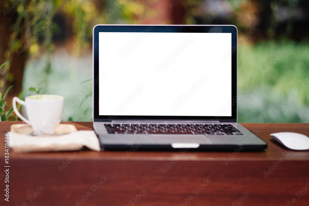 Front view of cup and laptop on table in office and background in the coffee shop Front view of cup and laptop on table in office and background in the coffee shop