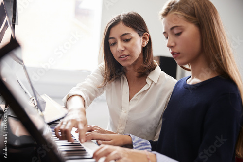 Fototapeta Kobieta uczeń z nauczycielem gry na pianinie w lekcji muzyki