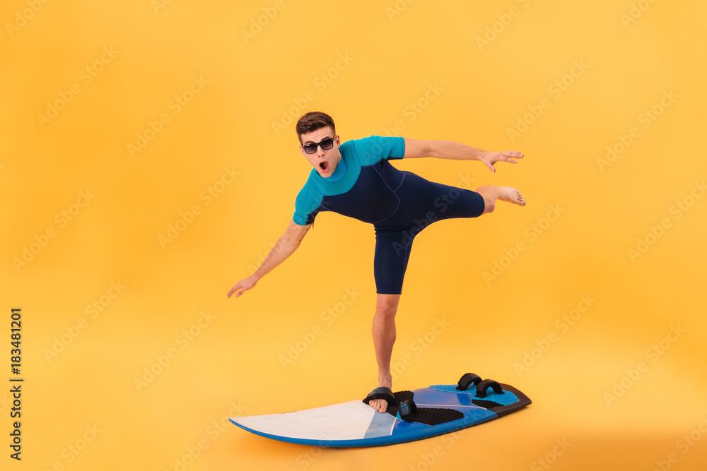 Picture of Funny surfer in wetsuit and sunglasses using surfboard