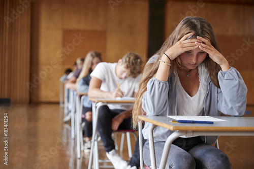 Anxious Teenage Student Sitting Examination In School Hall photo