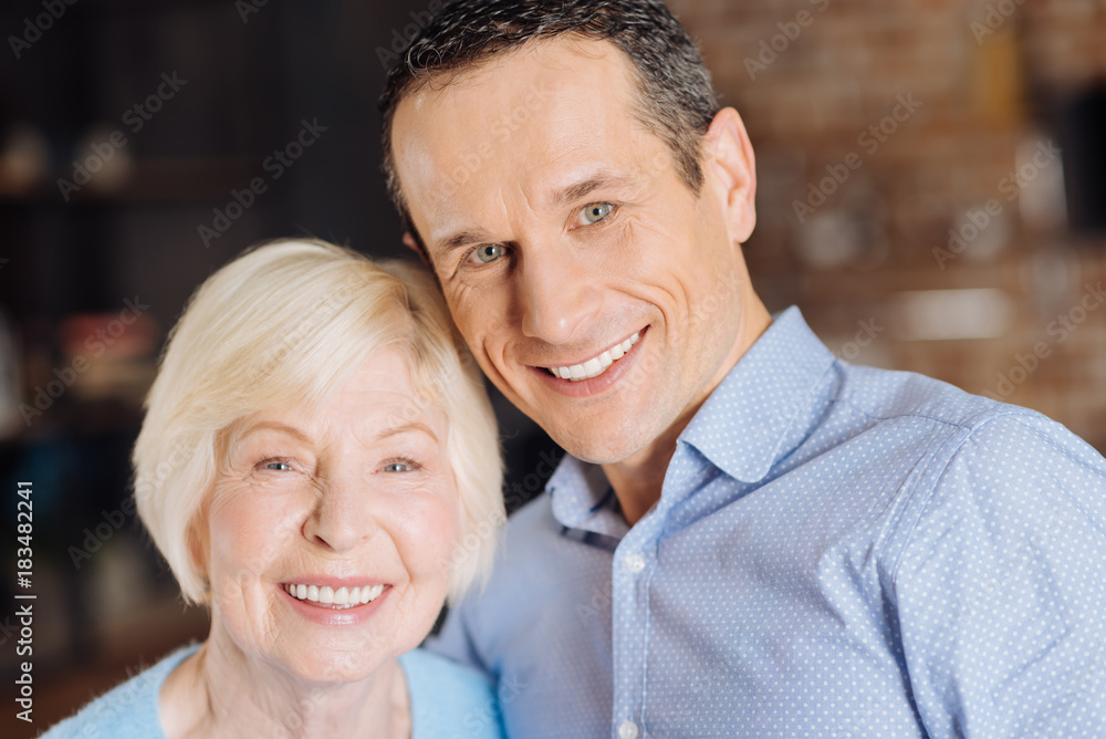 Family portrait. The portrait of a cheerful elderly woman and her charming young son smiling brightly at the camera Family portrait. The portrait of a cheerful elderly woman and her charming young son smiling brightly at the camera