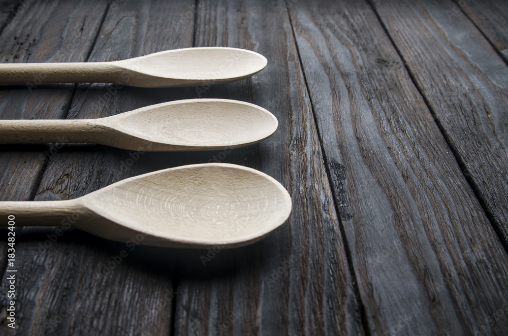 different spices in wooden spoons on a black wooden background different spices in wooden spoons on a black wooden background