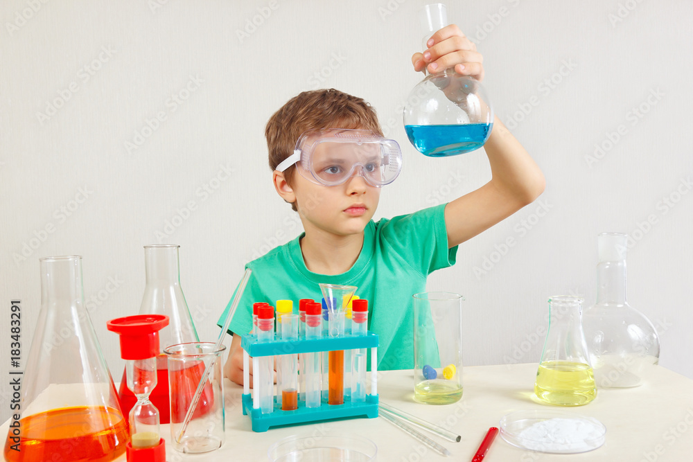 Little smart boy in safety goggles doing chemical experiments in the laboratory Little smart boy in safety goggles doing chemical experiments in the laboratory