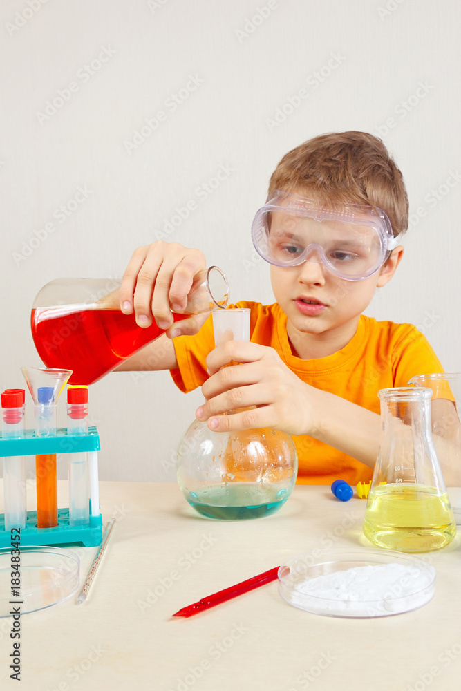 Young pensive boy in safety glasses studies chemical practice in the laboratory Young pensive boy in safety glasses studies chemical practice in the laboratory