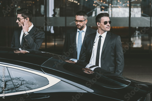 bodyguards going with businessman and reviewing territory near car photo