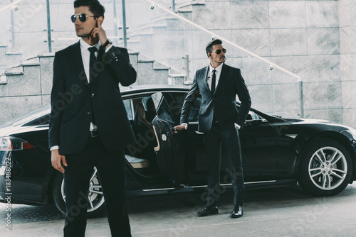 bodyguards in sunglasses standing at car and waiting for politician photo