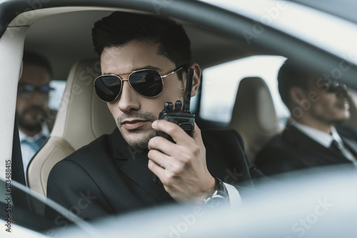 bodyguard in sunglasses talking by portable radio © LIGHTFIELD STUDIOS