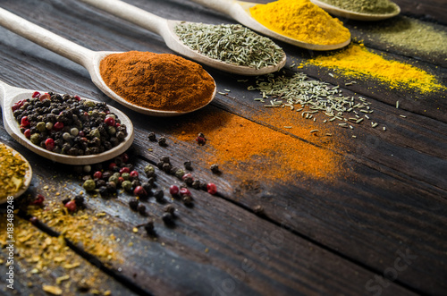 Fototapeta Naklejka Na Ścianę i Meble -  different spices in wooden spoons on a black wooden background