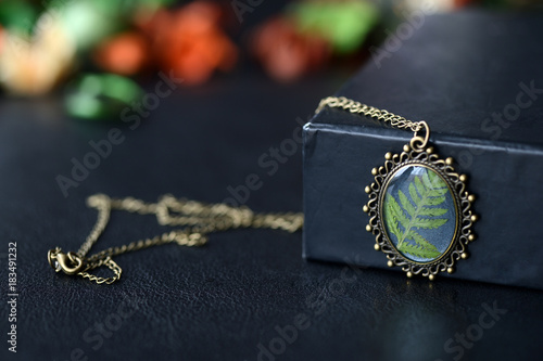 Resin pendant with fern leaf on a dark background close up