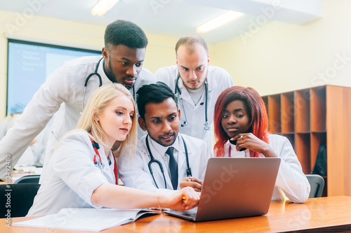 Multiracial team of young doctors working on laptop computer in medical office.