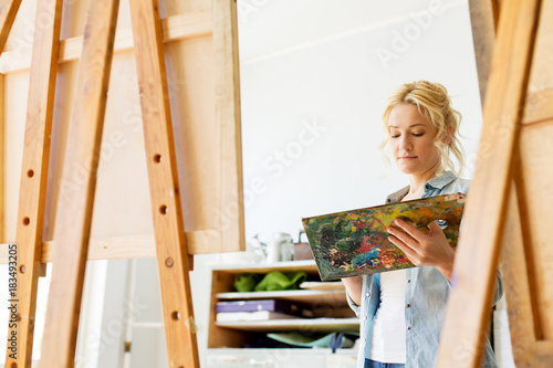 woman with easel painting at art school studio
