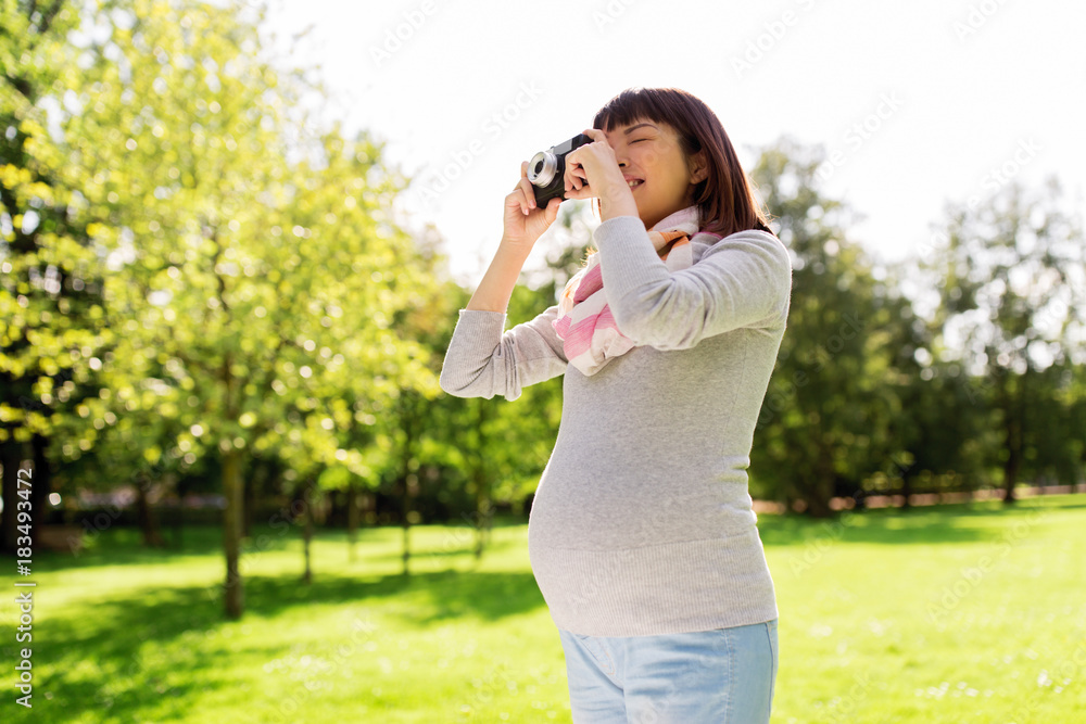 happy pregnant asian woman with camera at park
