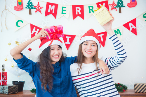 Two beautiful asian girl frind holding christmas gift box and smile in party at home photo