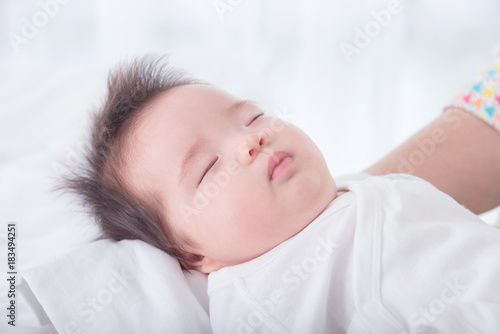 Little asian baby girl wearing white cloth sleeping on her mother arm