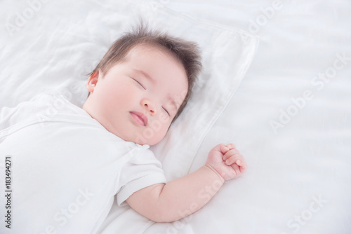 Little asian baby girl wearing white cloth sleeping on white bed