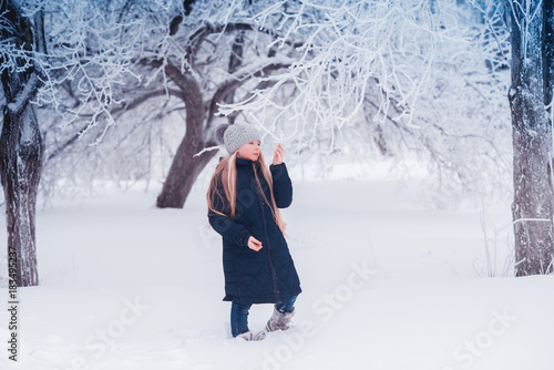 Winter girl blowing snow. Beauty Joyful Teenage Model Girl having fun in winter park. Beautiful girl laughing outdoors. Enjoying nature. photo