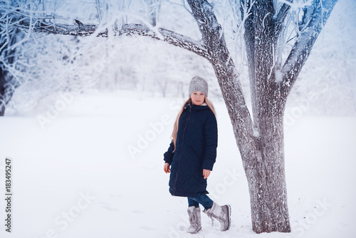 Winter girl blowing snow. Beauty Joyful Teenage Model Girl having fun in winter park. Beautiful girl laughing outdoors. Enjoying nature. photo