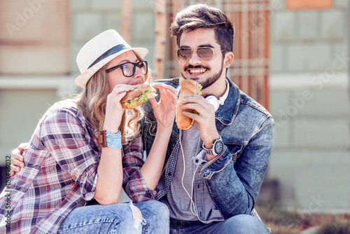 Young couple in love,guy and girl sitting and eating sandwich.