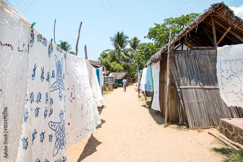 weiße Tücher und Decken hängen entlang der Gehwege im Dorf auf Nosy Komba / Madagaskar