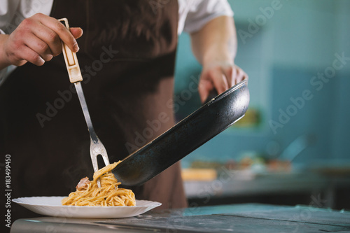Chef serves spaghetti carbonara on the plate in restaurante