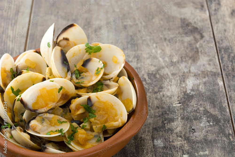 Clams with marinera sauce.Almejas a la marinera. Spanish recipe on wooden table Clams with marinera sauce.Almejas a la marinera. Spanish recipe on wooden table