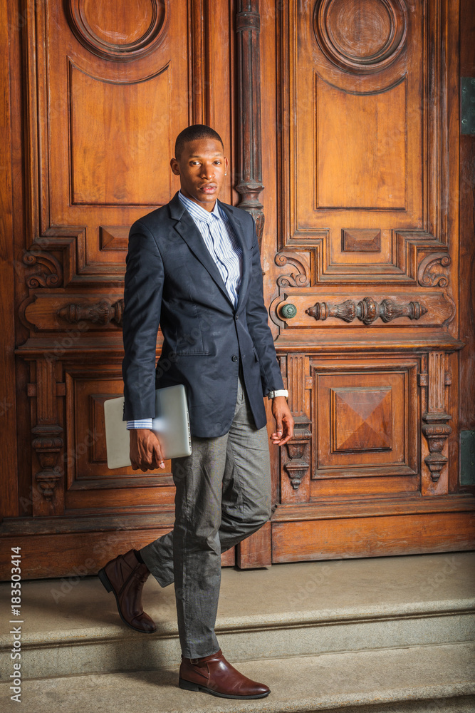 lobby trembling Hurricane Wearing black blazer, gray pants, brown leather shoes, hand carrying laptop  computer, a young African American businessman walking down stairs from  vintage style office door way, looking forward. Stock Photo | Adobe