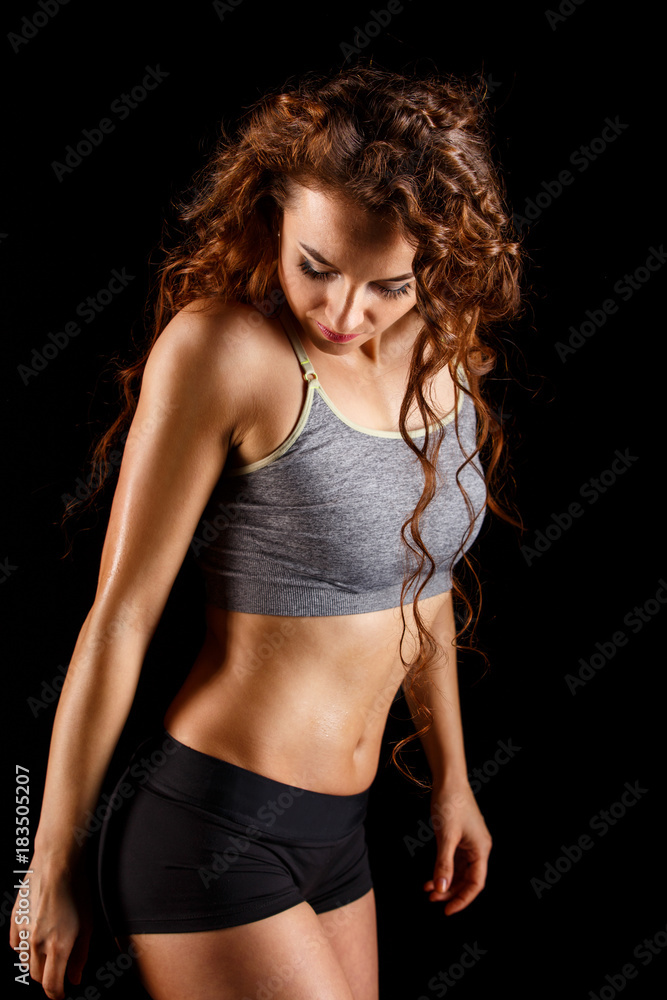 Attractive fit woman standing over dark background. Fitness concept image
