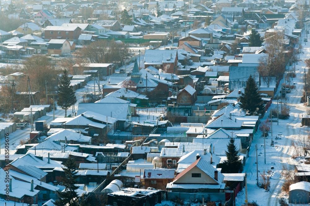 Fototapeta premium Rustic houses in winter, light smoke from the pipes. Top view with blur.