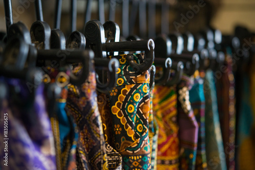 Colorful women's dresses on hangers in a retail shop. Fashion and shopping concept.