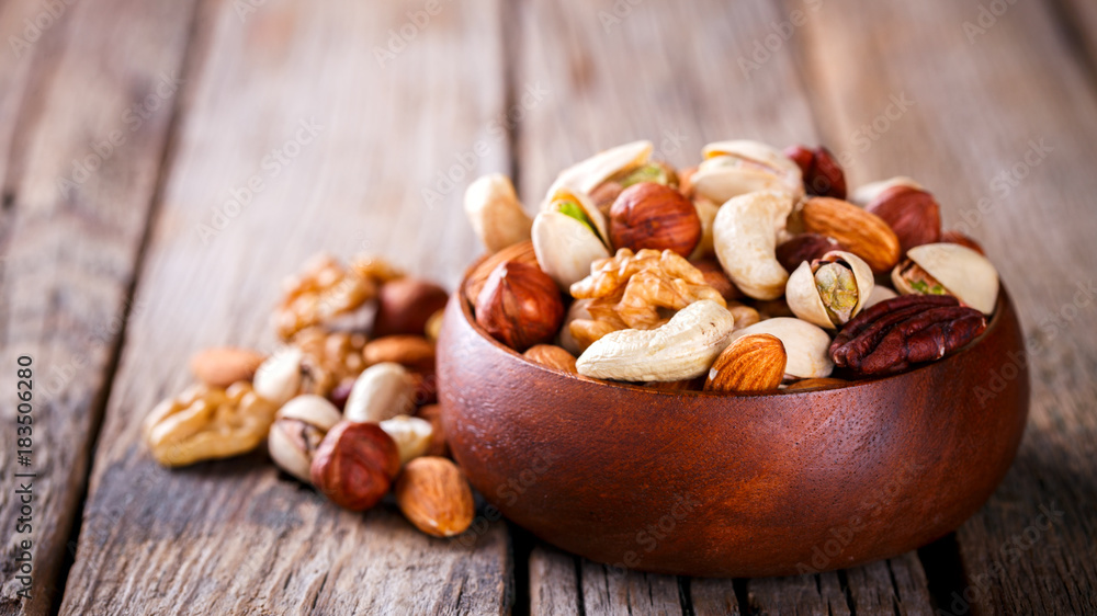 Nuts Mixed in a wooden plate.Assortment, Walnuts,Pecan,Almonds,Hazelnuts,Cashews,Pistachios.Concept of Healthy Eating.Vegetarian.Copy space.selective focus. Nuts Mixed in a wooden plate.Assortment, Walnuts,Pecan,Almonds,Hazelnuts,Cashews,Pistachios.Concept of Healthy Eating.Vegetarian.Copy space.selective focus.