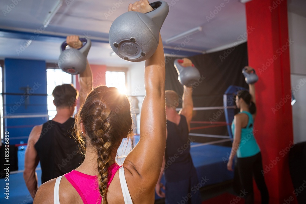 Fototapeta premium Rear view of young athletes lifting kettles