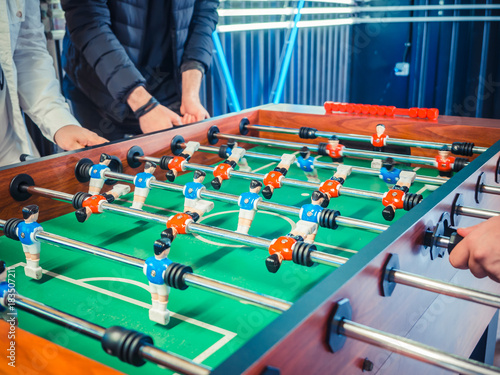 Cropped image of active people playing foosball. table soccer plaers. Friends play together table football