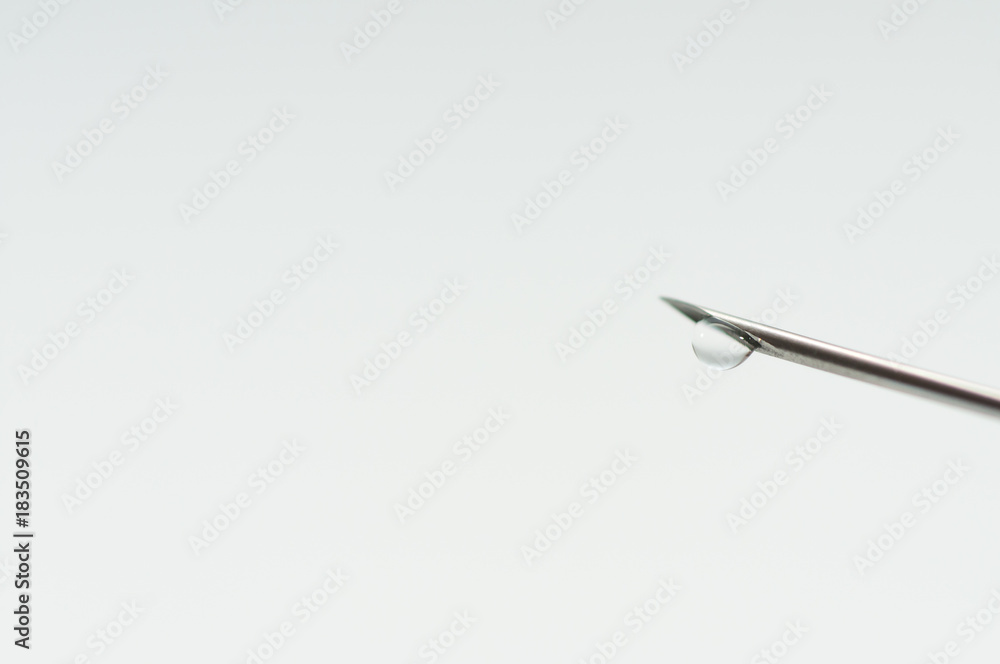 Medical needle, focus on the liquid drop isolated on white background. Medical needle, focus on the liquid drop isolated on white background.