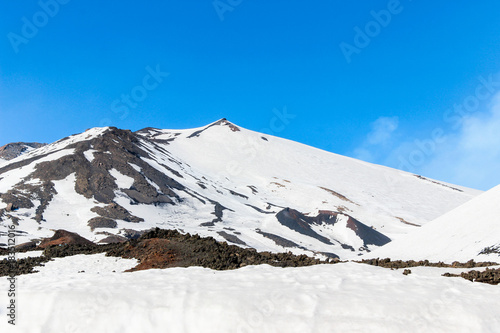 winter landscape of snow on black lava stone on mountain Etna