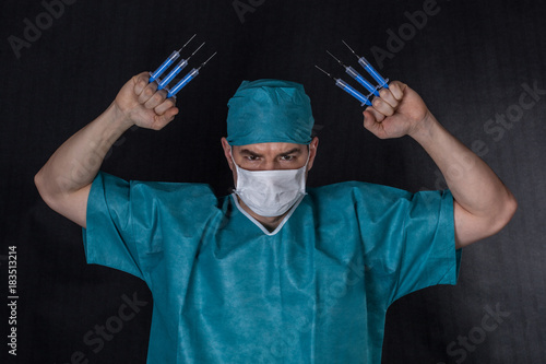 Surgeon in scrubs with syringes claws on a black background