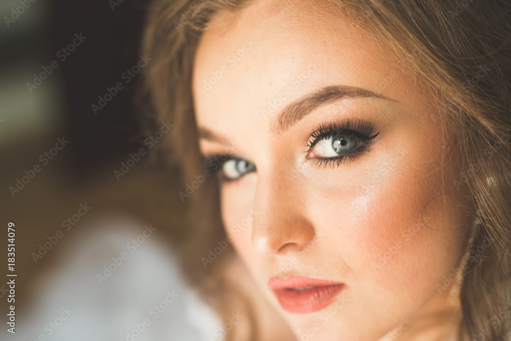 Gorgeous bride in robe posing and preparing for the wedding ceremony face in a room Gorgeous bride in robe posing and preparing for the wedding ceremony face in a room