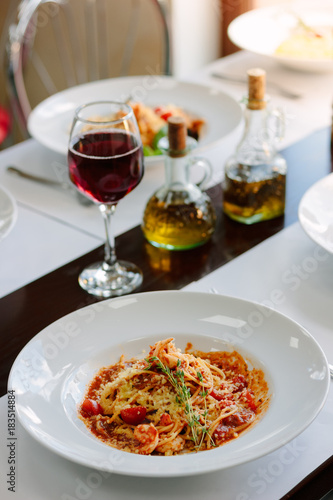 Italian traditional pasta with tomatoes and seafood on restaurant table.
