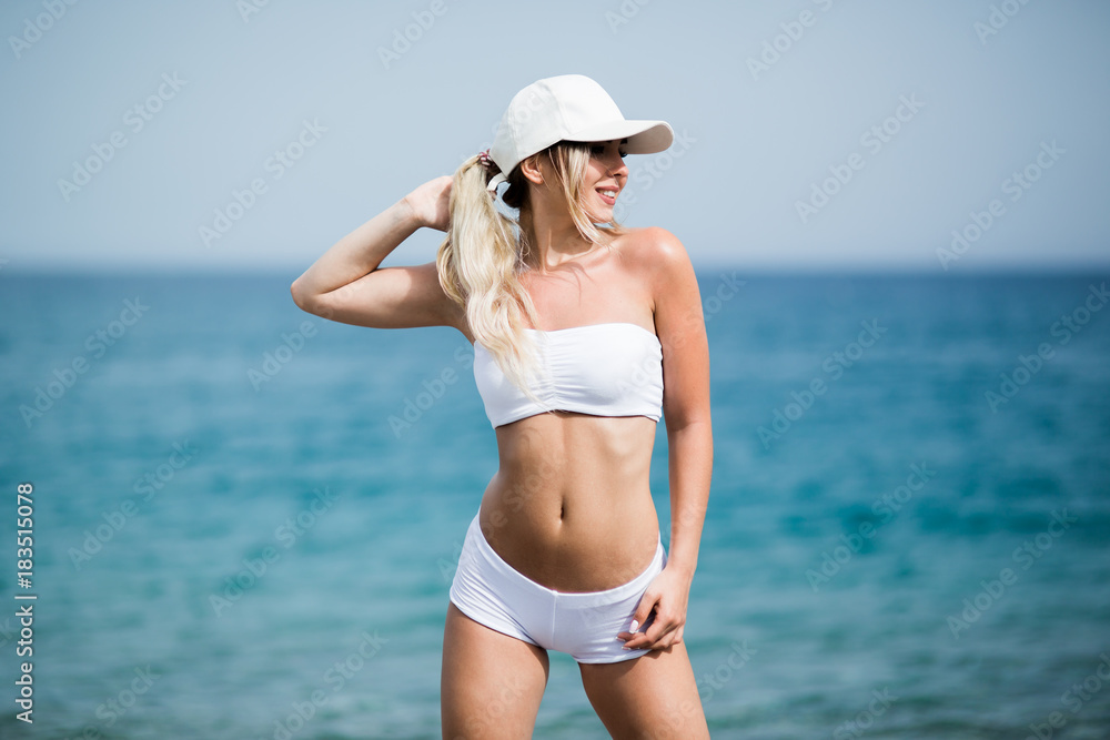 Fitness girl with a perfect body is smiling near the sea