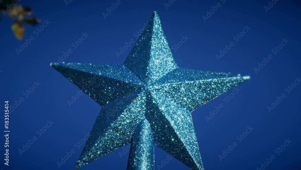 A shiny blue Christmas star against a blue sky A shiny blue Christmas star against a blue sky