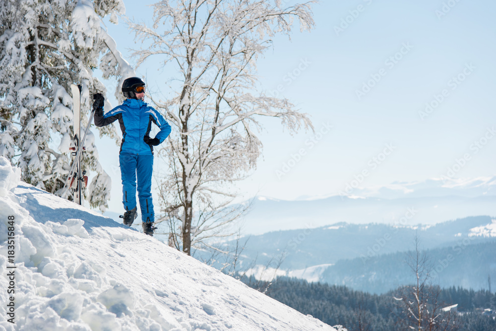 Full length shot of a happy female skier resting the slope with her skis in the mountains at winter ski resort copyspace