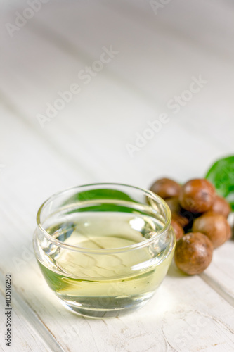 Natural and organic macadamia oil on a white wooden table.